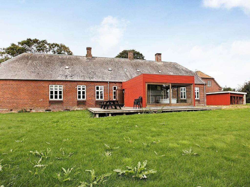 ein rotes Backsteinhaus mit einem großen grünen Feld in der Unterkunft Holiday Home Åstedvej in Åsted