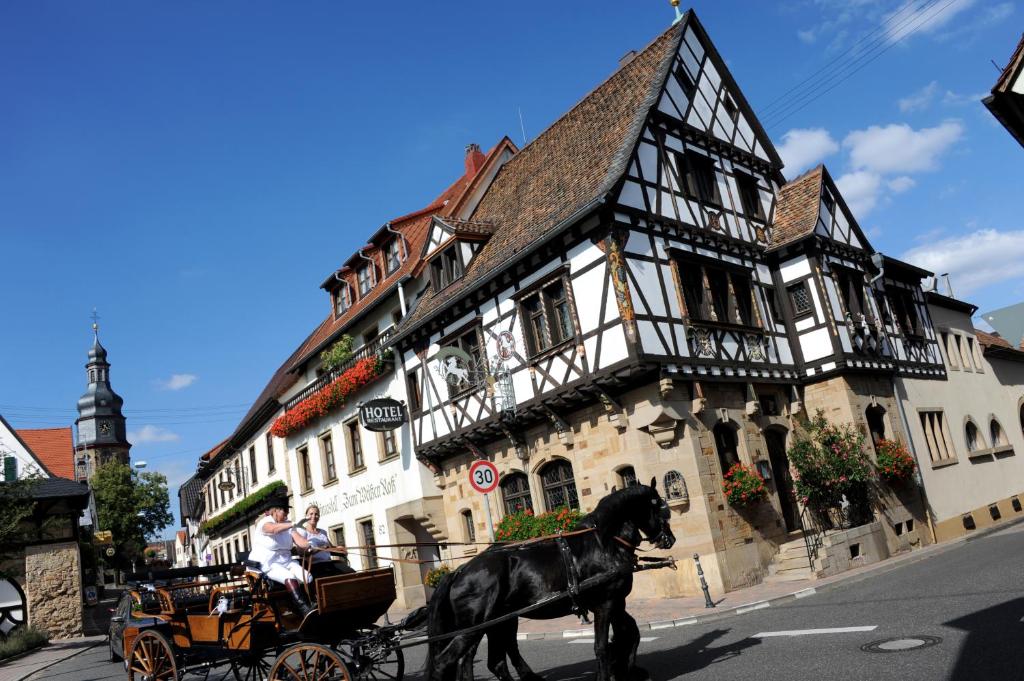 a horse drawn carriage in front of a building at Weinkastell Zum Weissen Ross in Kallstadt