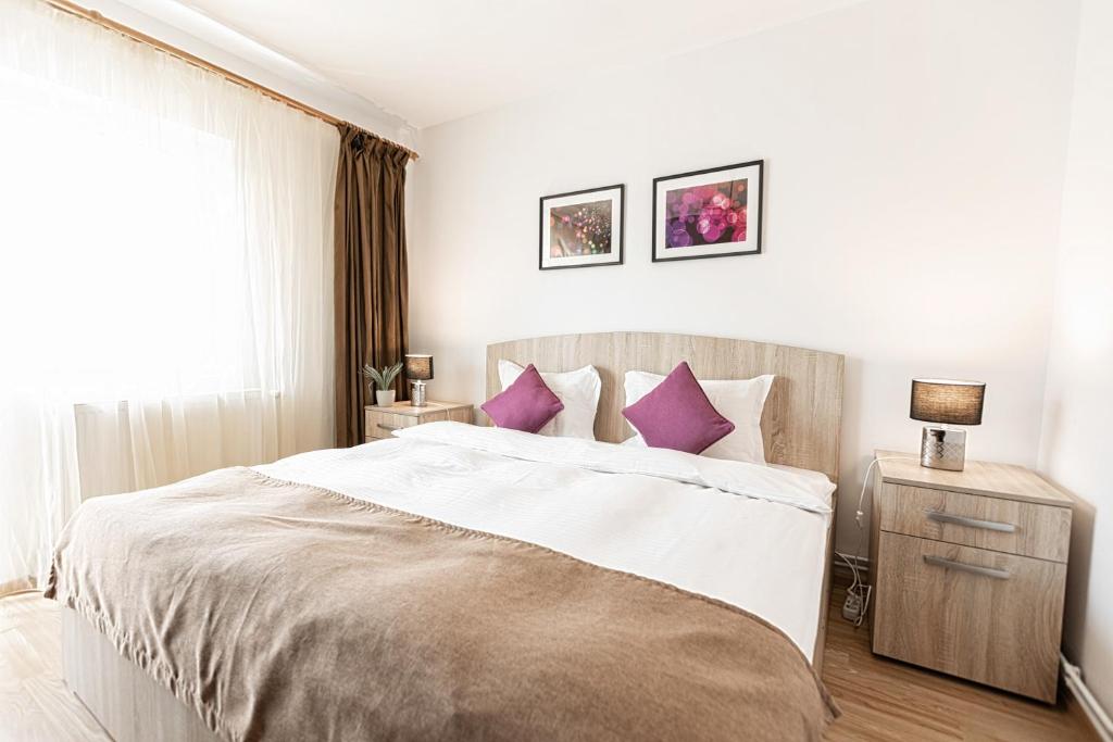 a bedroom with a large bed with purple pillows at Montana Apartment City Center in Braşov