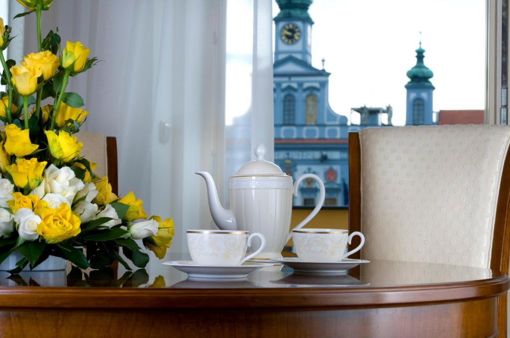 una mesa con dos tazas y una tetera y flores en Zvon Design Suites, en České Budějovice