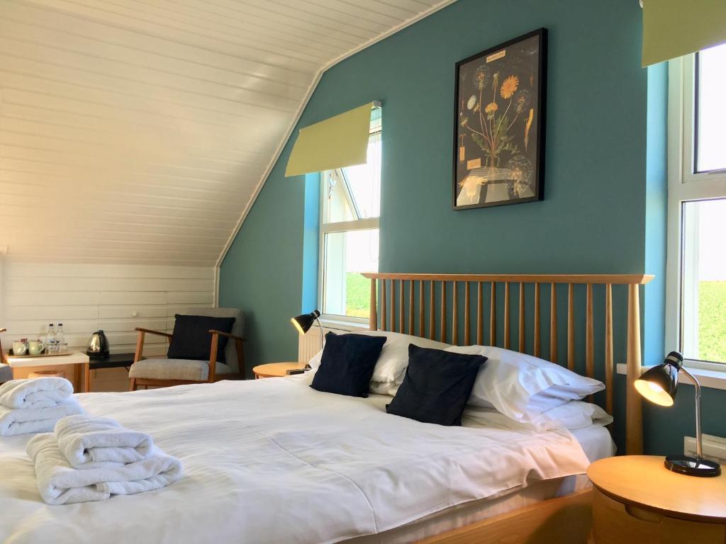 a bedroom with a large white bed with blue walls at St George's Country House in Perranporth