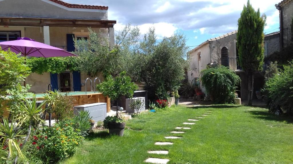 - un jardin avec une maison et un parasol dans l'établissement Gites du Mas Gibert à SAUSSINES entre Nimes et Montpellier, à Saussines