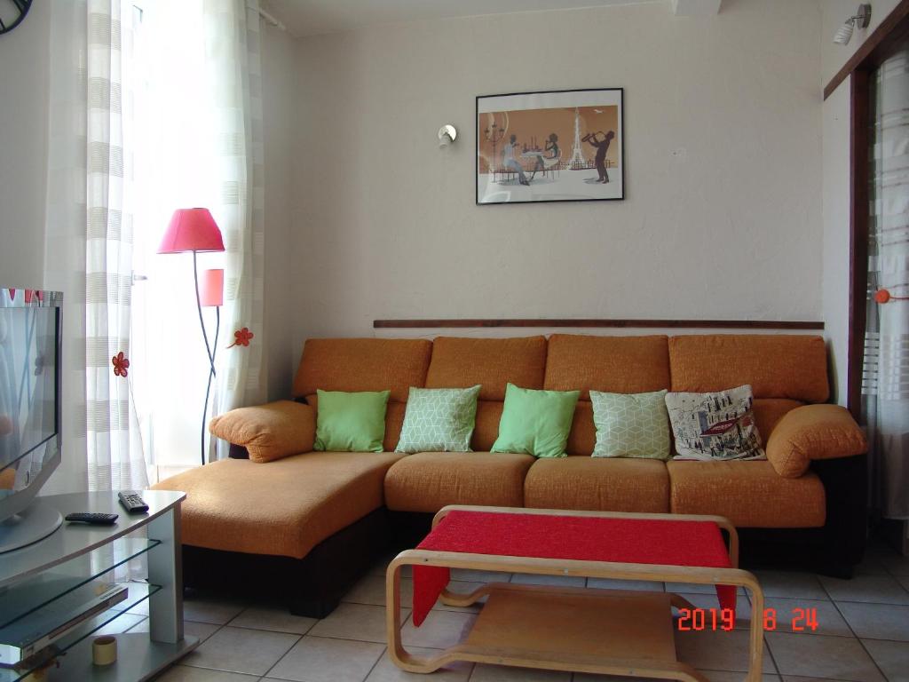 アクス・レ・テルムにあるApartment Natikのリビングルーム(オレンジ色のソファ、緑色の枕付)