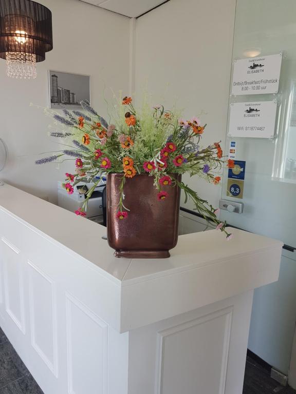 a vase with flowers sitting on top of a counter at Stad &amp; Strandhotel Elisabeth in Vlissingen