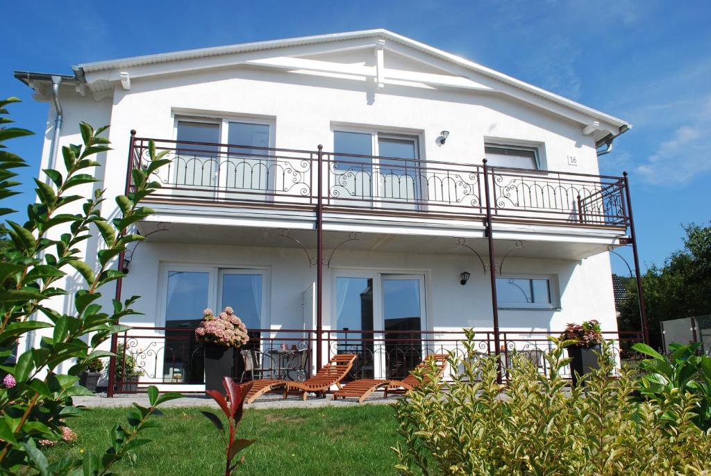 a white house with a balcony and chairs at Villa-Panter in Sassnitz