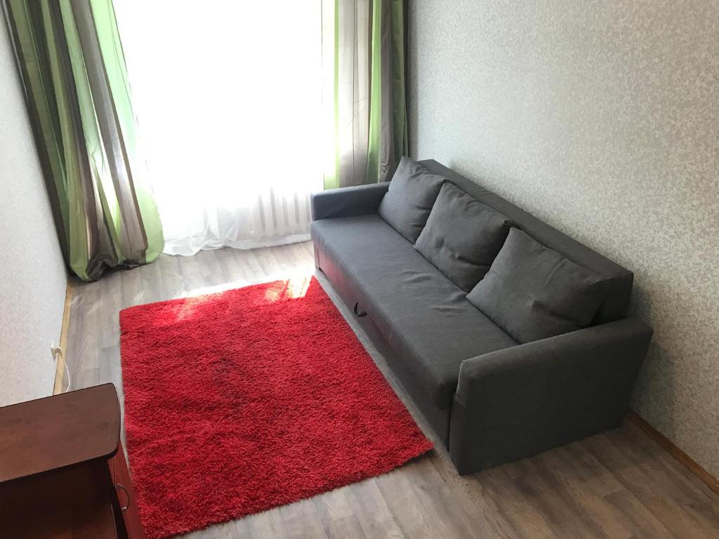モスクワにあるApartment G-Kvartal at Vershininaの赤い敷物のあるリビングルームのソファ