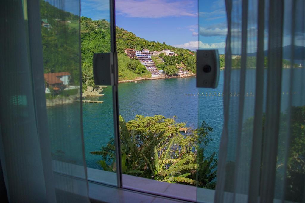 een raam met uitzicht op een rivier bij Pousada Casa da Praia Angra in Angra dos Reis