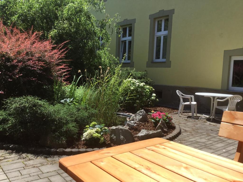 a garden with a wooden bench and a table at Ferienwohnungen An der Bimmelbahn Wernigerode in Wernigerode