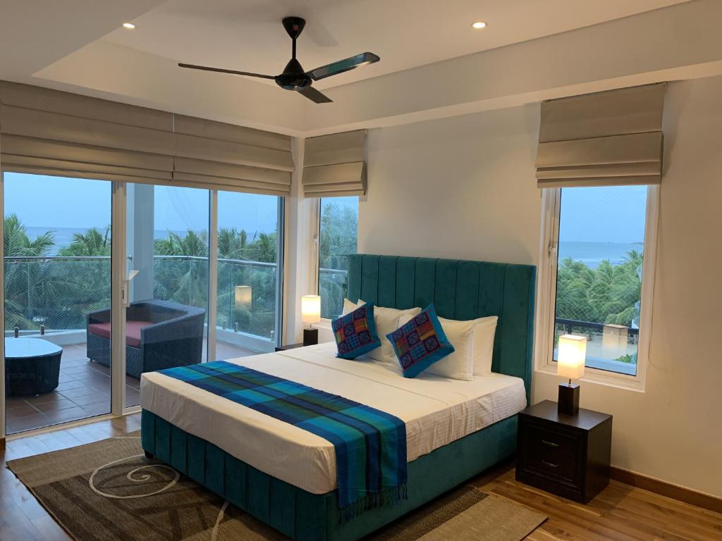 a bedroom with a bed and a large window at Nilaveli Ocean Front Luxury Apartments in Trincomalee
