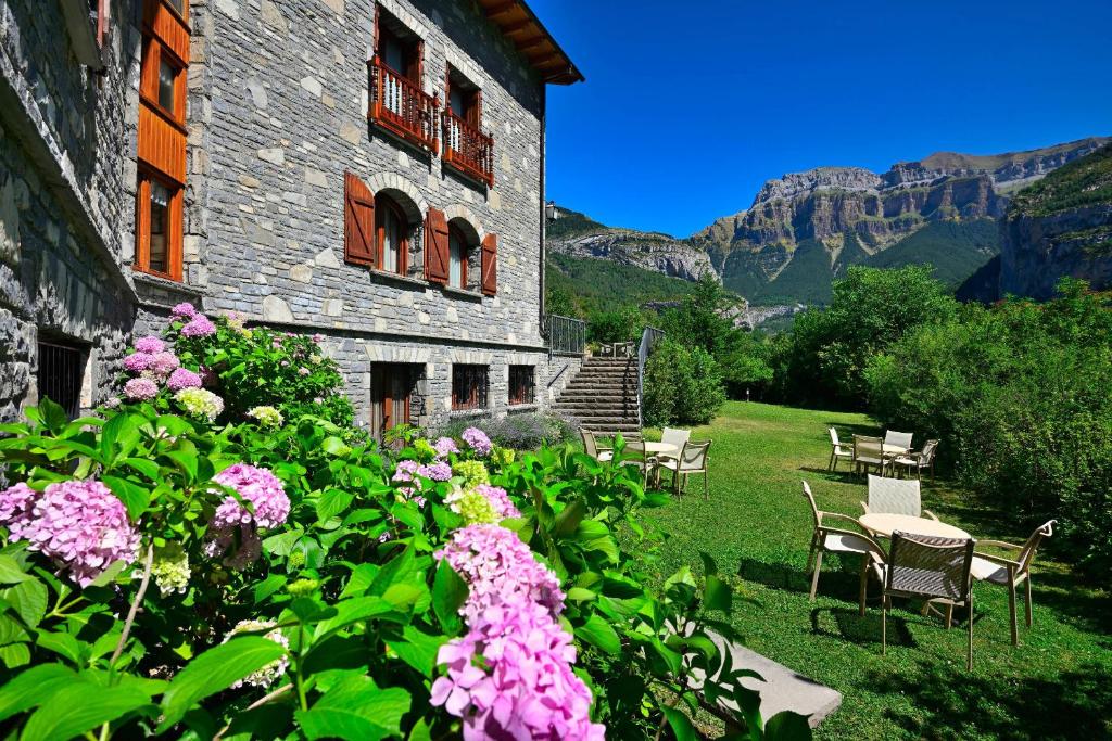 a garden with chairs and flowers in front of a building at Hotel Abetos in Torla-Ordesa