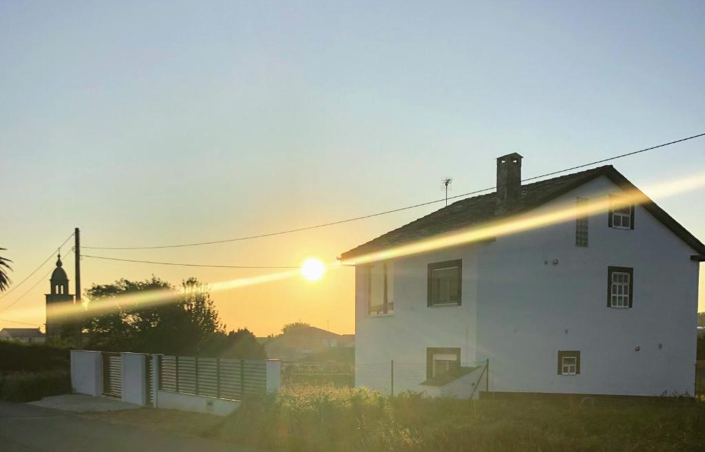 una casa blanca con la puesta de sol detrás de ella en Barranca de San Miguel en Barreiros
