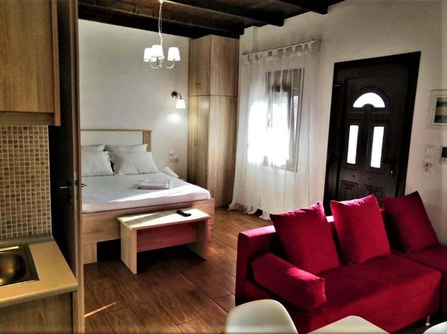 ein Wohnzimmer mit einem roten Sofa und einem Bett in der Unterkunft The Little Gem Under The Rocks in Kastraki