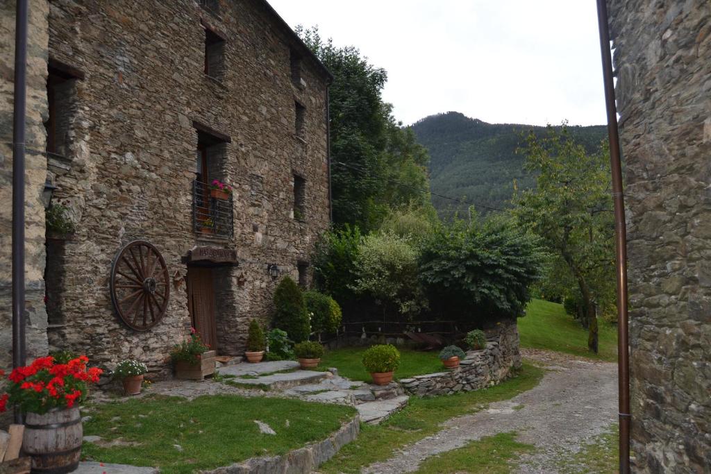 - une vue extérieure sur un bâtiment en pierre avec un jardin dans l'établissement Mas La Casanova, à Queralbs