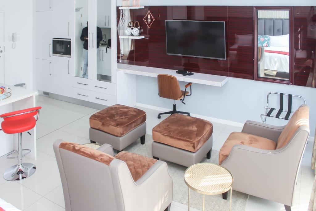 un soggiorno con mobili bianchi e TV di Green Avenue Apartments a Gaborone