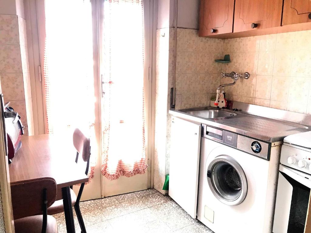 a kitchen with a washing machine and a table at Milkyway Apartment in Viareggio