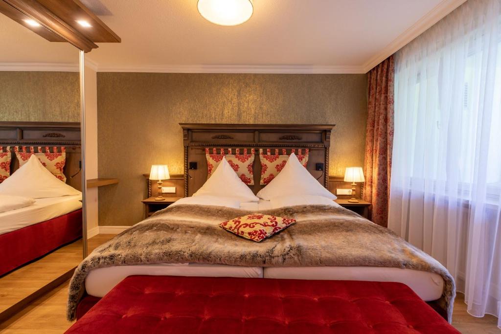 バート・ヴァルトゼーにあるParkhotelのベッドルーム1室(赤毛布付きの大型ベッド1台付)