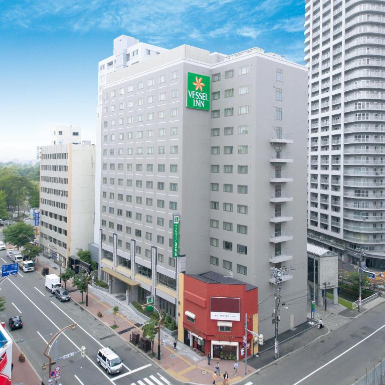 a large white building with a green sign on it at Vessel Inn Sapporo Nakajima Park in Sapporo
