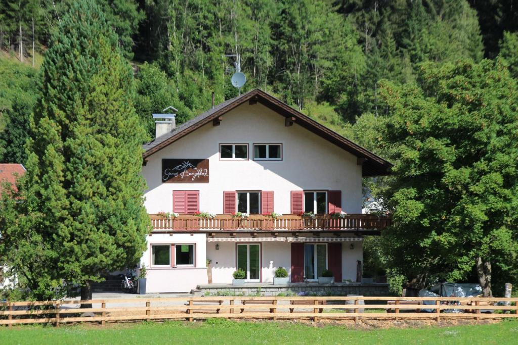 ein großes weißes Haus mit einem Balkon und Bäumen in der Unterkunft Garni Bergblick in Prags