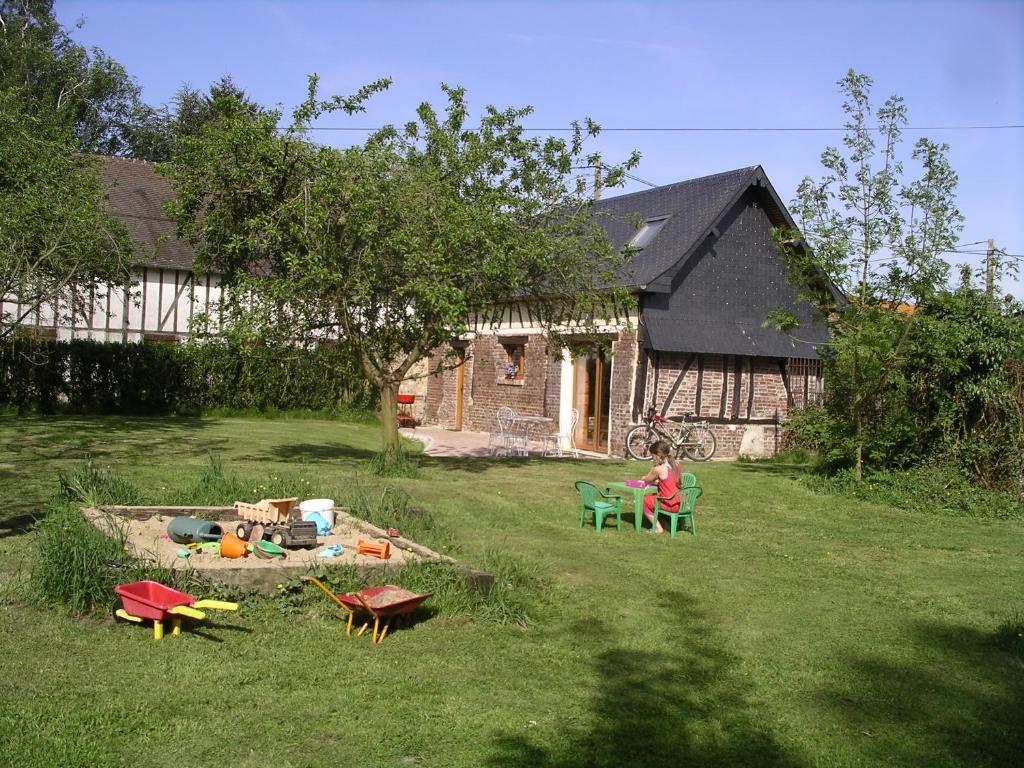 a woman sitting on a chair in front of a house at Gîte du Valcrocq 4/5 pers in Le Bec-Thomas