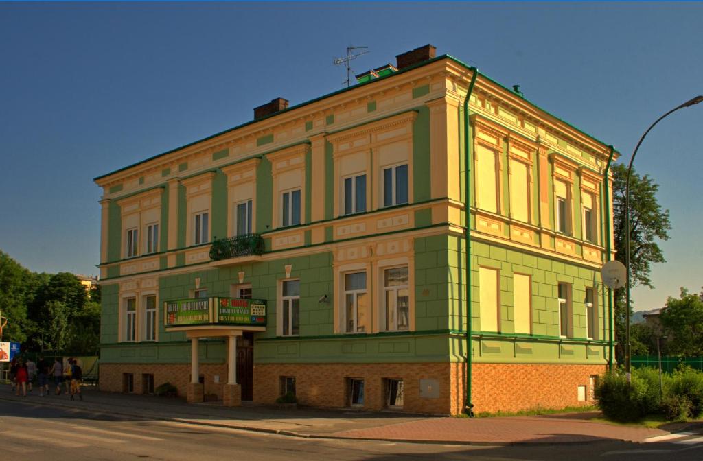 a yellow and green building on the corner of a street at Hotel Jagielloński in Sanok