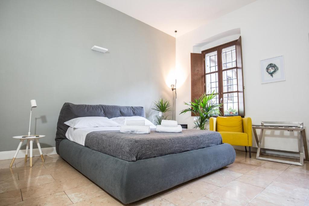 una camera con un grande letto e una sedia gialla di Antiche Colonne Suite a Verona