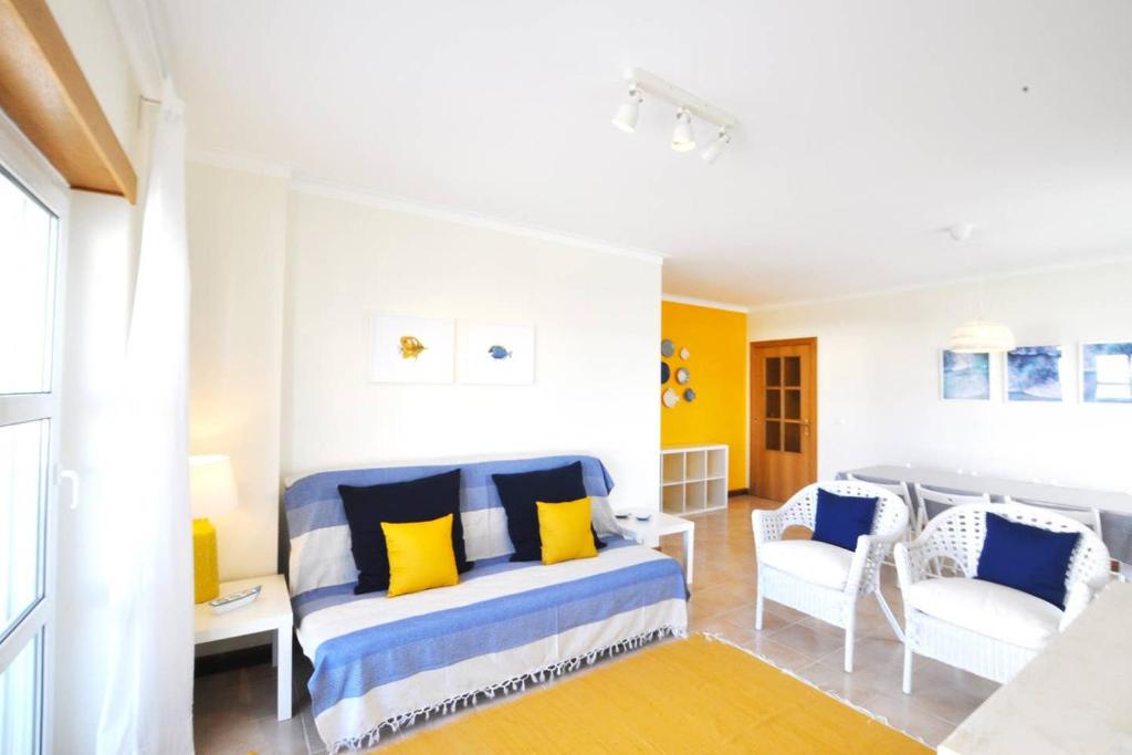 a room with a bed with yellow and blue pillows at Casa Carapau in Ferrel