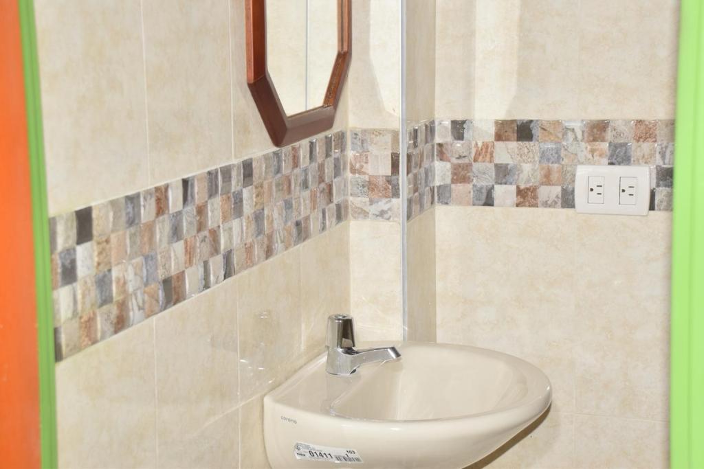 lavabo blanco en el baño con azulejos en la pared en Nirvana House Calima Darien en Calima