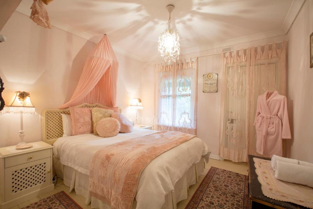 1 dormitorio con 1 cama con dosel rosa en Jasmine's Barossa Valley Cottage, en Lyndoch