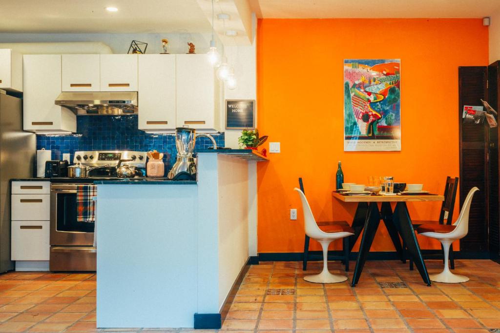 uma cozinha com paredes cor de laranja e uma mesa com cadeiras em Renovated Historic Coconut Grove Cottage Home em Miami