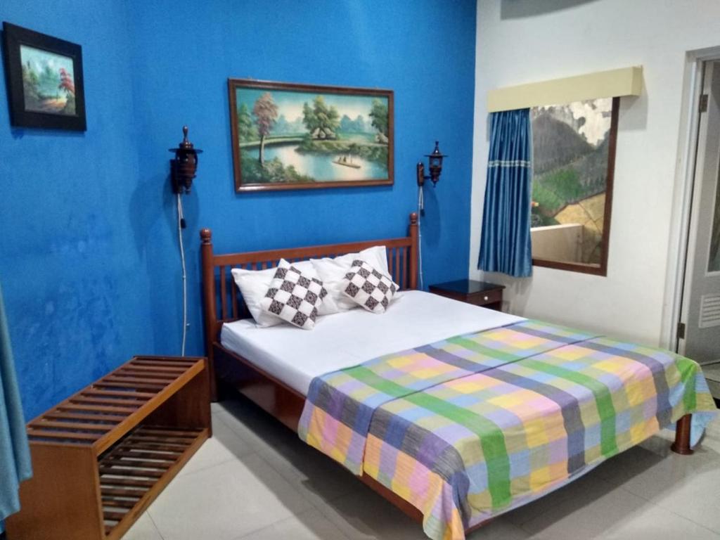 a bedroom with a bed and a blue wall at Enny's Guest House in Malang