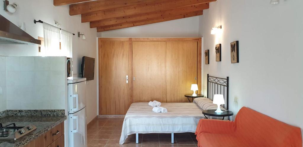 Habitación con cama, sofá y cocina. en Tranquilidad y naturaleza a 800m Playa Migjorn en Playa de Migjorn
