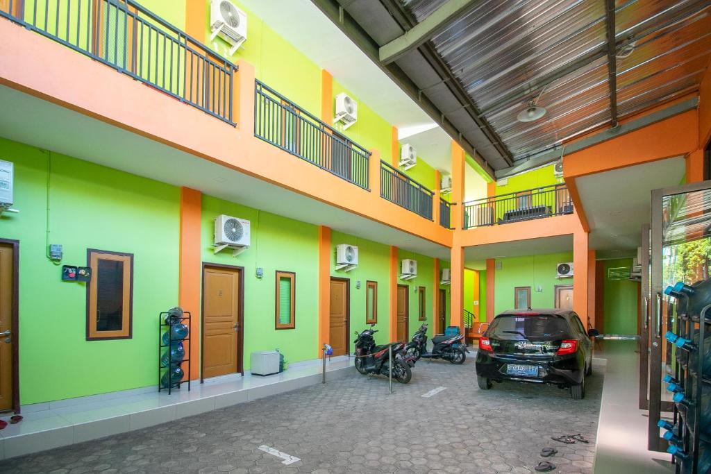 a building with a car parked in a parking lot at RedDoorz near Kejaksan Station Cirebon 2 in Cirebon