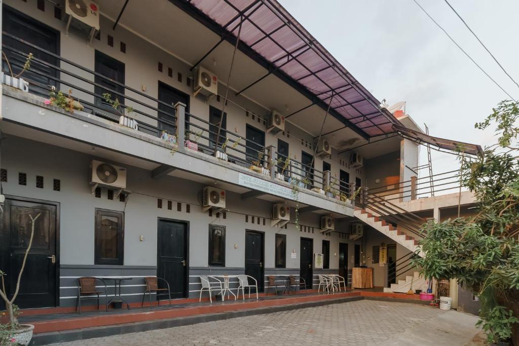 a building with a balcony with tables and chairs at RedDoorz Syariah near Ciledug Station in Cirebon