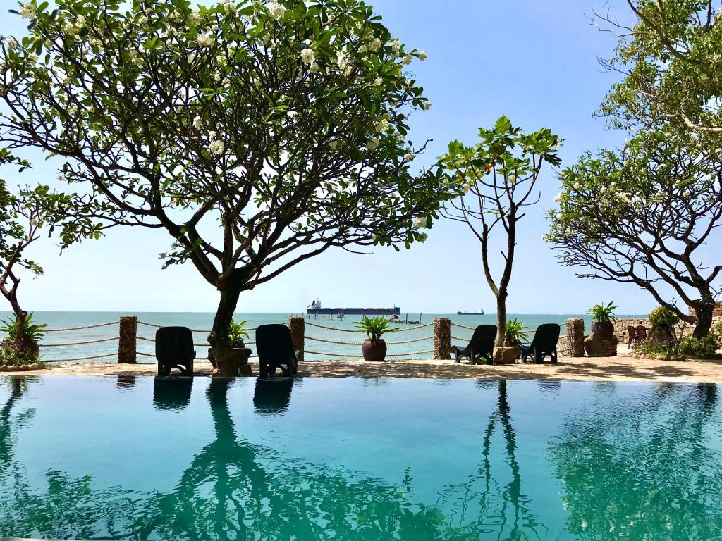 a pool with chairs and trees in front of the water at Binh An Village Vung Tau in Vung Tau
