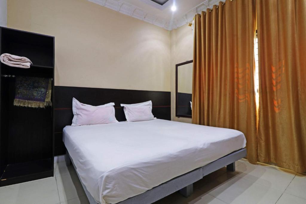 um quarto com uma cama com lençóis brancos e almofadas em Utama Syariah em Pekanbaru