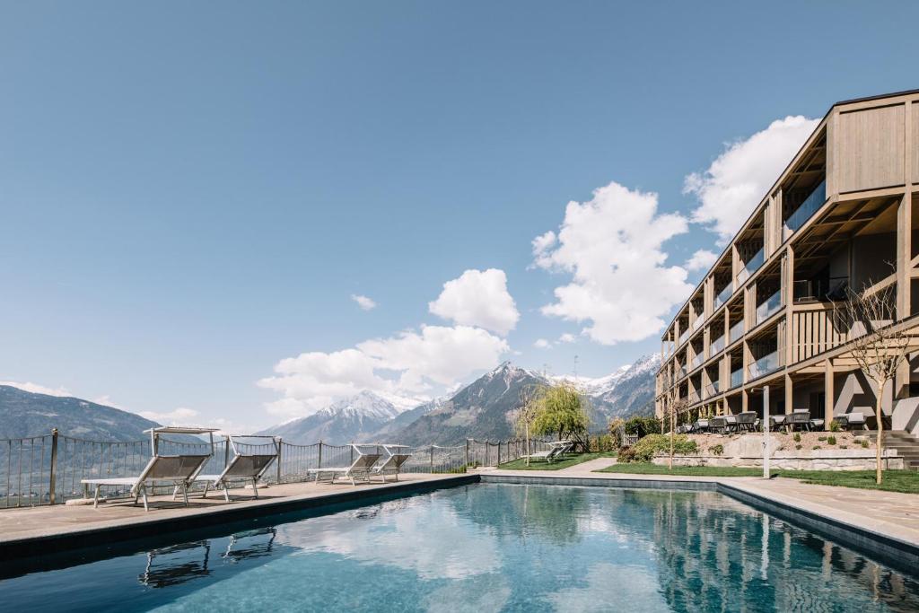 una piscina de hotel con montañas en el fondo en Panoramic Suites Winzerhöhe, en Scena