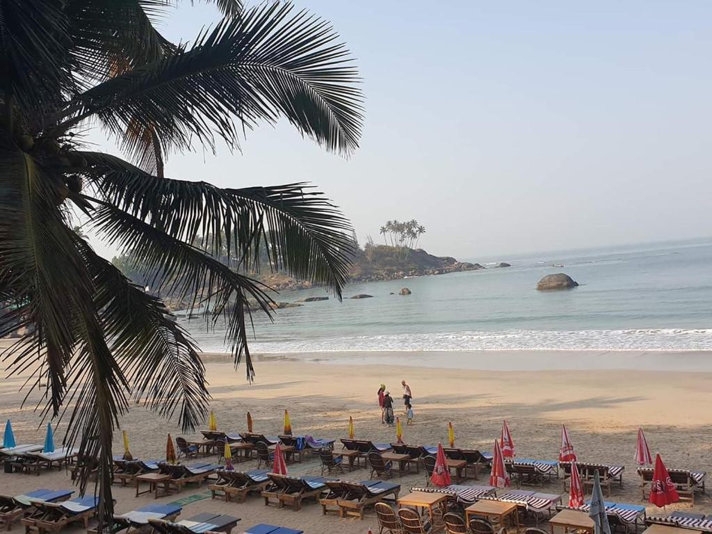 una playa con sillas y sombrillas y el océano en Alexmarie Guest house 5 min to candolim Beach, en Aguada