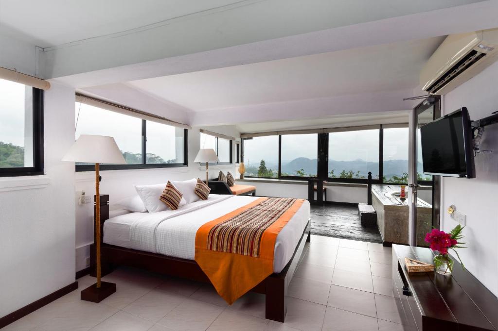 a bedroom with a bed and a tv and windows at The Theva Residency in Kandy