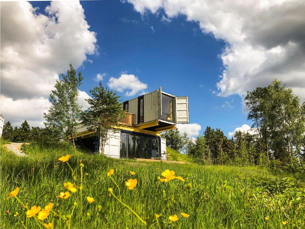 a house on a hill with a field of flowers at BERGHEIM Container Loft in Schöneck