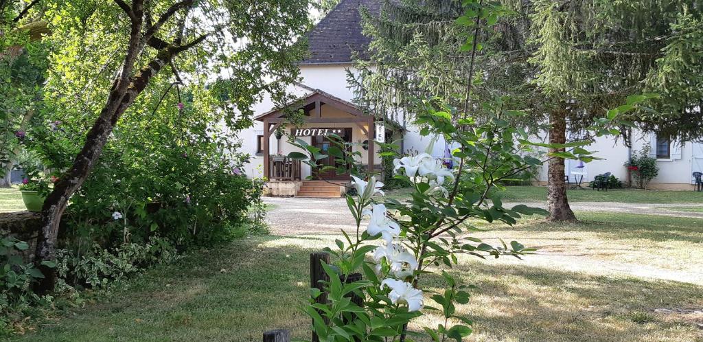 une maison avec des fleurs blanches devant elle dans l'établissement Hotel du Parc, à Thonac