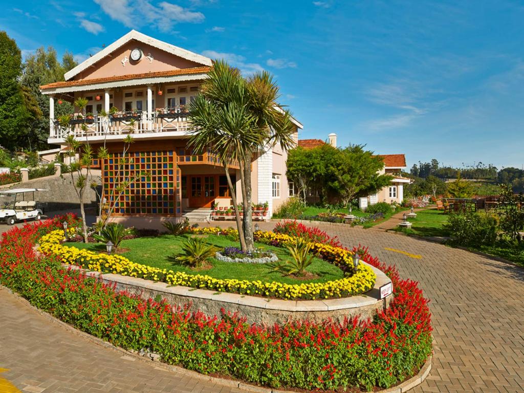 a house with a flower garden in front of it at Club Mahindra Derby Green, Ooty in Ooty