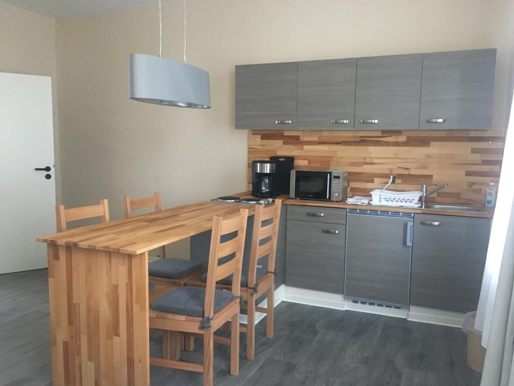 a kitchen with a wooden table with chairs and a microwave at Pension am Pollingpark Haus II in Dessau