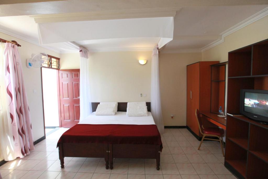 1 dormitorio con 1 cama y TV. en Coastgate Hotel en Mombasa