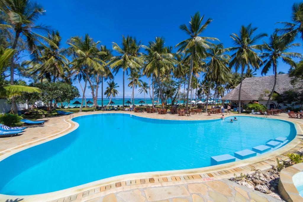 una piscina en el complejo con palmeras en el fondo en Diani Sea Lodge - All Inclusive, en Diani Beach