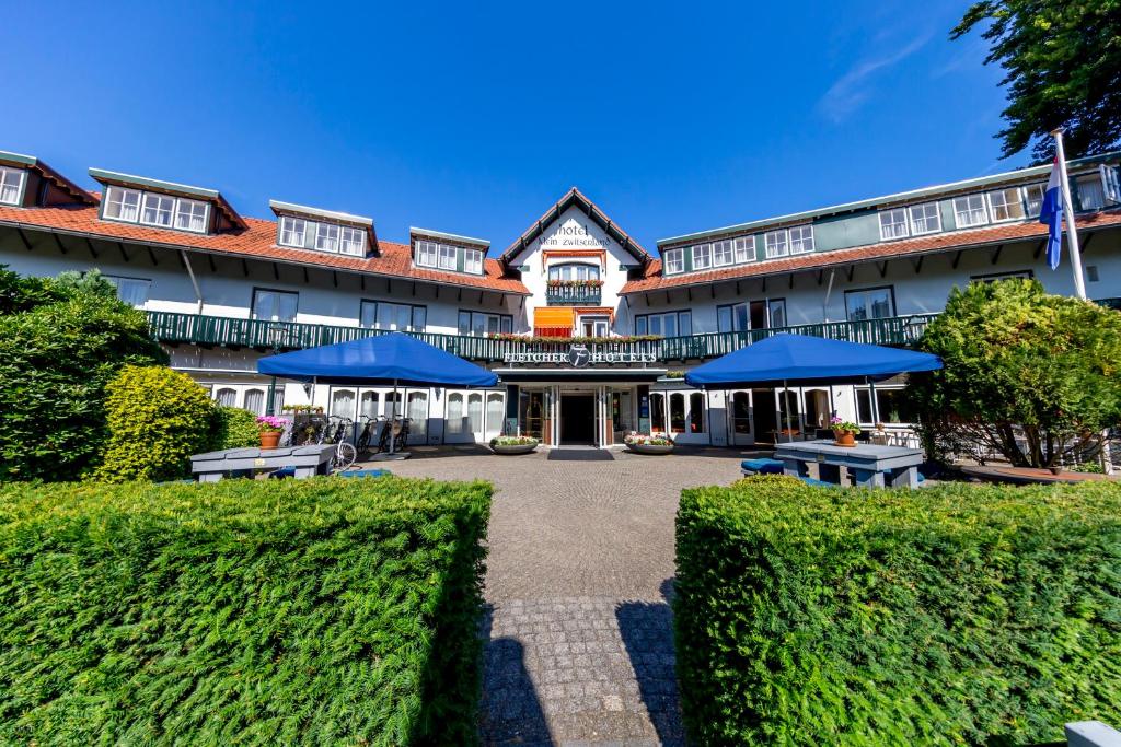 a hotel with blue umbrellas in a courtyard at Fletcher Hotel-Restaurant Klein Zwitserland in Heelsum