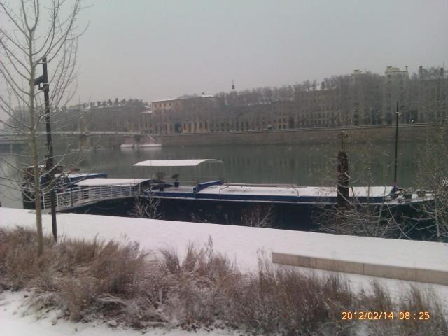 a boat is docked on a river in the snow at Chez Tatiana in Lyon