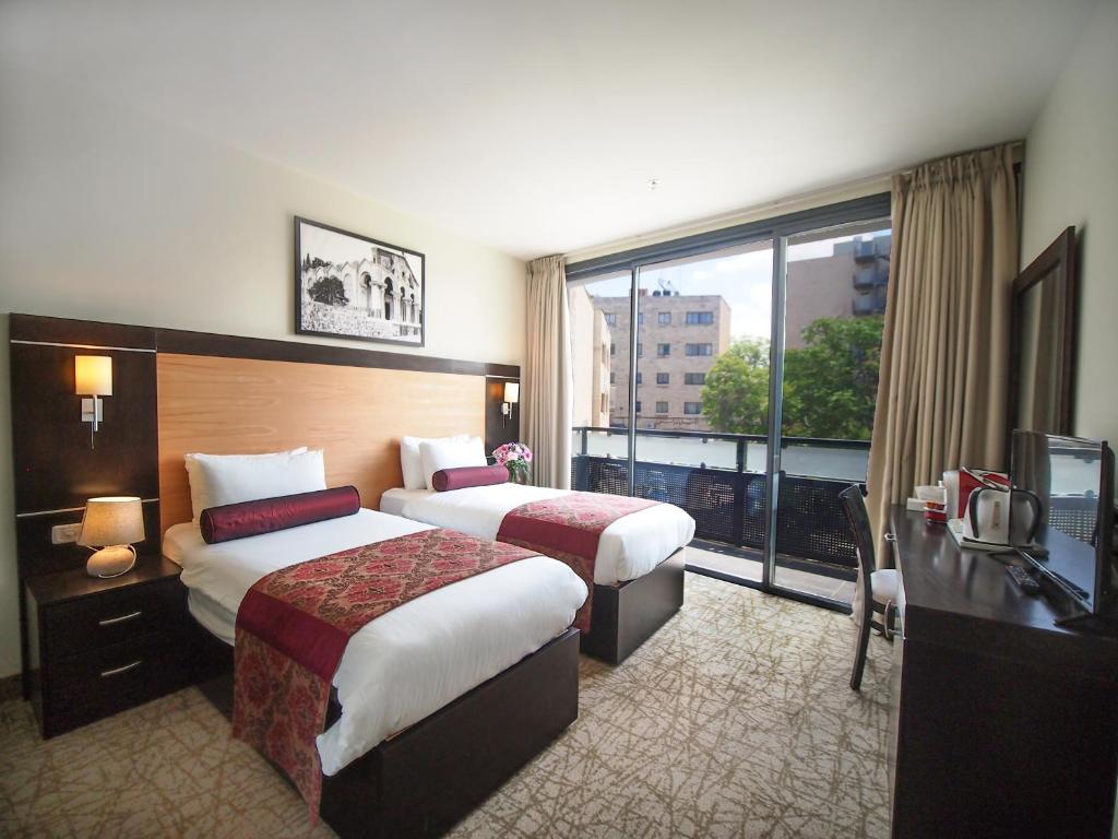 a hotel room with two beds and a large window at New Capitol Hotel - Jerusalem in Jerusalem