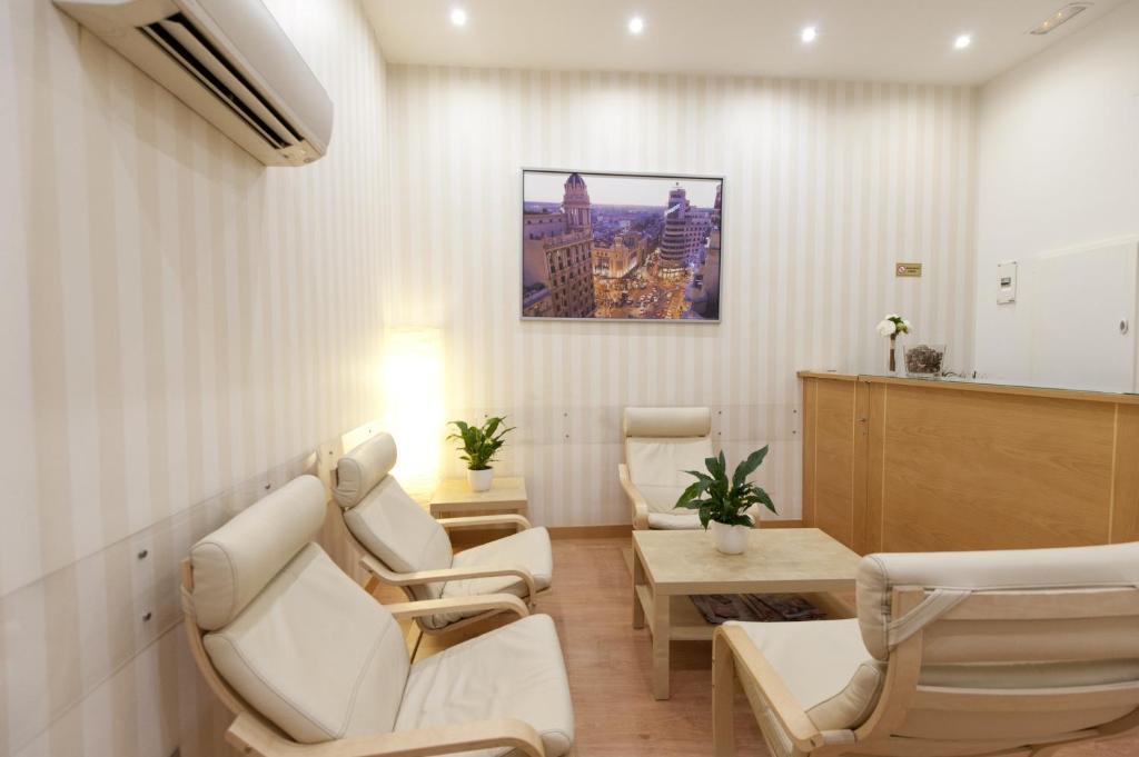 a waiting room with white chairs and a table at Hostal Abami II in Madrid