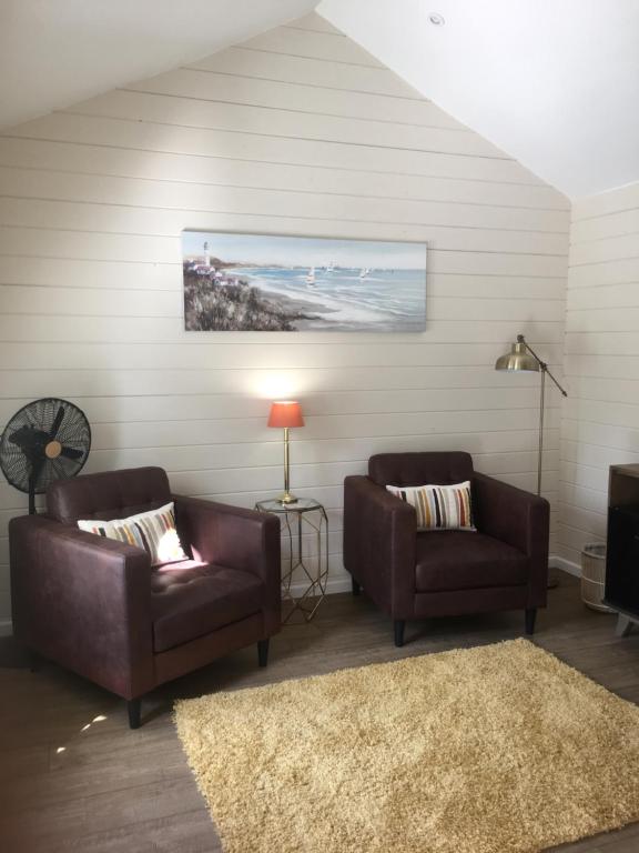 a living room with two leather chairs and a rug at Willow House B&B in West Wittering