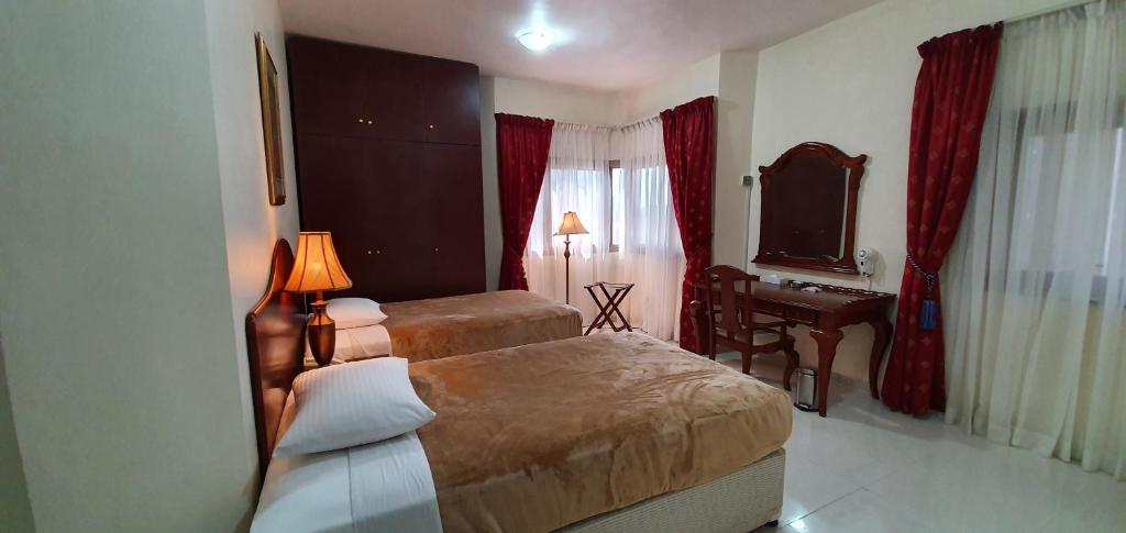 a hotel room with two beds and a desk at Ivory Hotel Apartments in Abu Dhabi